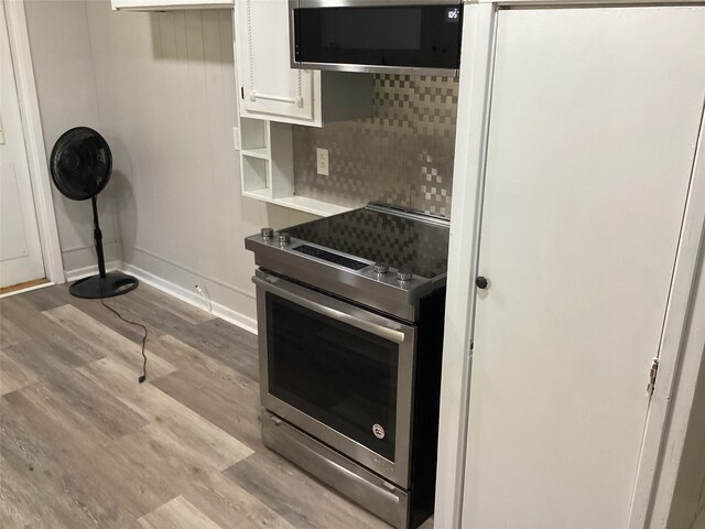 kitchen featuring white cabinets, light wood-type flooring, stainless steel appliances, and backsplash