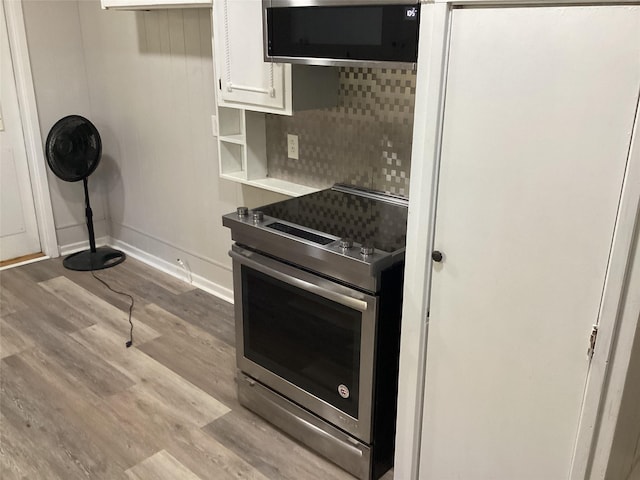 604 S Seaman St, Eastland, TX 76448 - kitchen with appliances with stainless steel finishes, white cabinets, wood finished floors, and baseboards