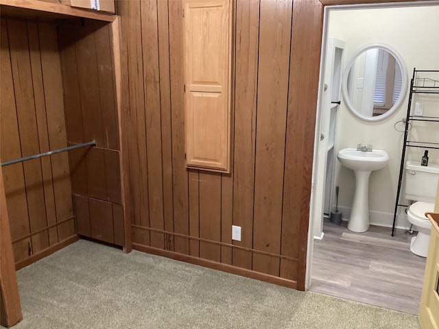 bathroom featuring wood walls, wood-type flooring, toilet, and sink