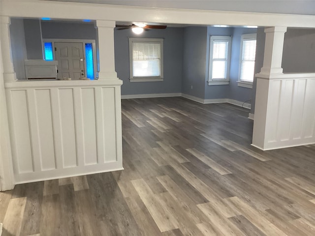 604 S Seaman St, Eastland, TX 76448 - unfurnished living room featuring decorative columns, dark wood finished floors, baseboards, and ceiling fan