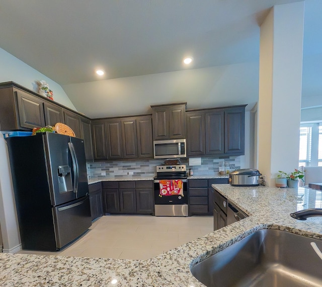 kitchen featuring dark brown cabinets, vaulted ceiling, ceiling fan, backsplash, and stainless steel appliances