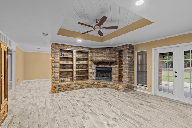 unfurnished living room with a brick fireplace, ceiling fan, crown molding, and french doors