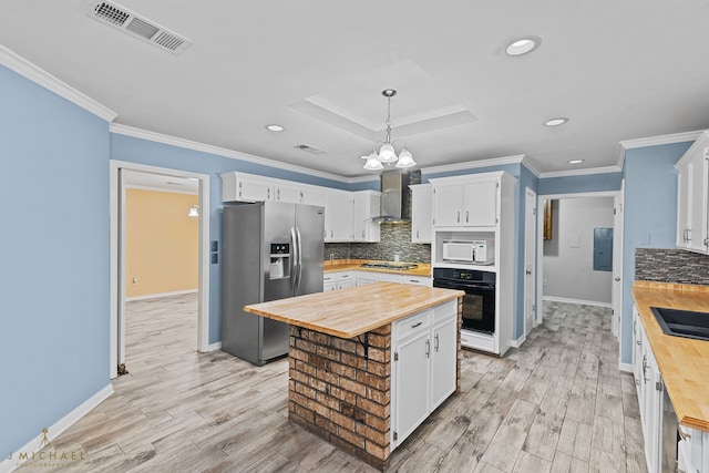 kitchen featuring butcher block countertops, white cabinetry, hanging light fixtures, and stainless steel appliances