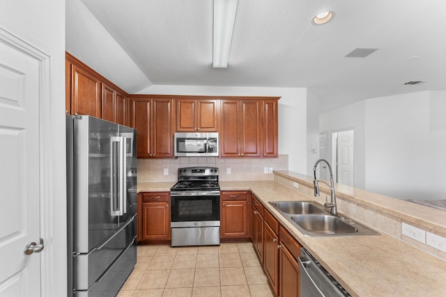 kitchen with sink, decorative backsplash, light tile patterned floors, kitchen peninsula, and stainless steel appliances