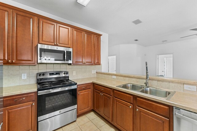 kitchen with tasteful backsplash, sink, light tile patterned floors, and appliances with stainless steel finishes