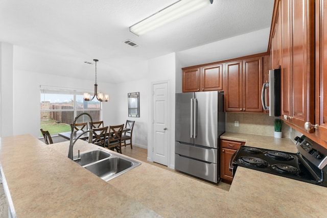 kitchen featuring appliances with stainless steel finishes, pendant lighting, sink, decorative backsplash, and a notable chandelier