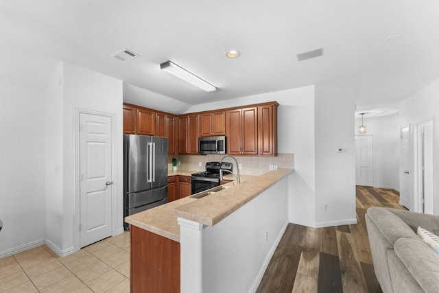 kitchen with appliances with stainless steel finishes, sink, backsplash, and kitchen peninsula