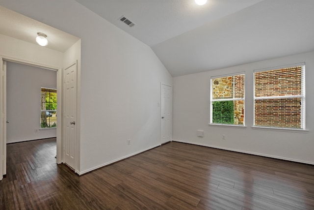 empty room with dark wood-type flooring, plenty of natural light, and lofted ceiling