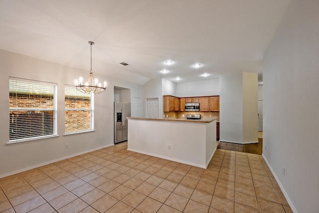 kitchen with a notable chandelier, pendant lighting, light tile patterned floors, and stainless steel appliances