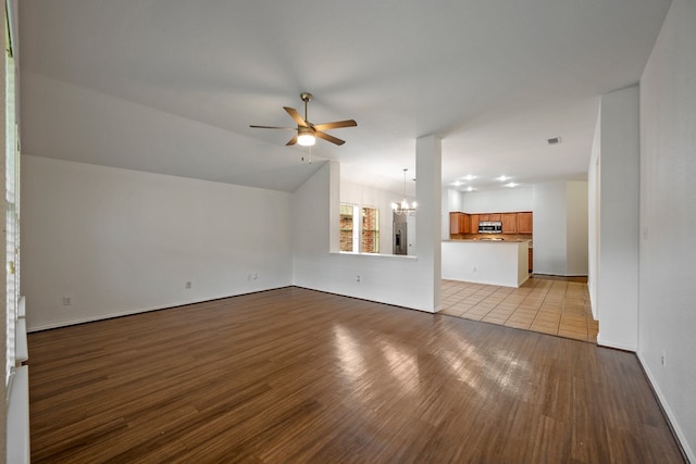 unfurnished living room featuring ceiling fan with notable chandelier and light hardwood / wood-style flooring