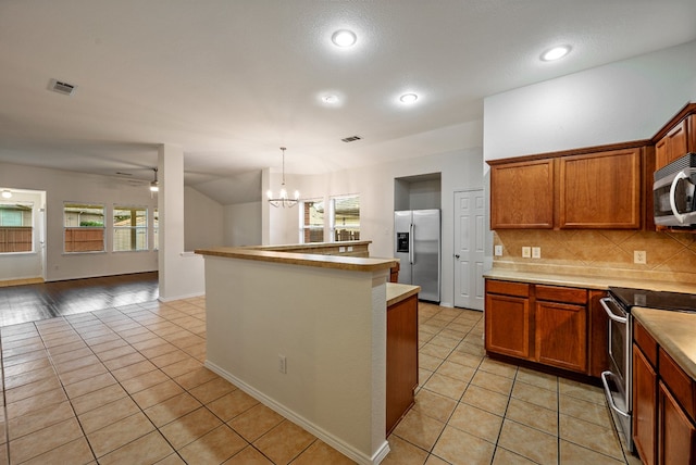 kitchen featuring hanging light fixtures, light tile patterned flooring, decorative backsplash, and appliances with stainless steel finishes