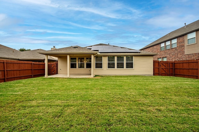 back of property with a patio, solar panels, and a yard