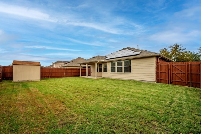 back of house with a patio, a yard, and a storage shed