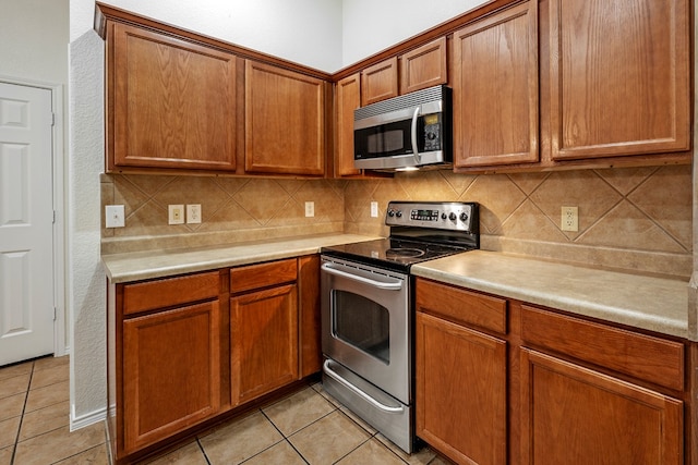 kitchen with tasteful backsplash, appliances with stainless steel finishes, and light tile patterned flooring