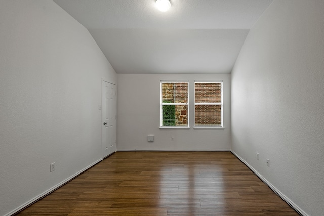 empty room featuring dark wood-type flooring and lofted ceiling