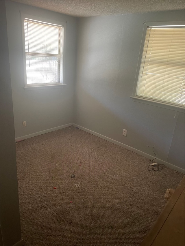 carpeted empty room with a textured ceiling