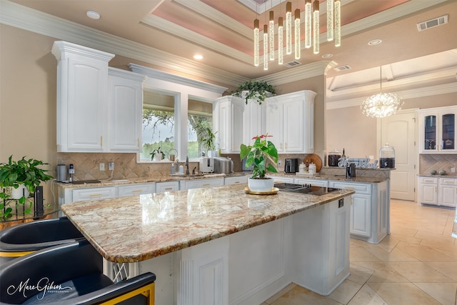 kitchen featuring white cabinets, decorative light fixtures, a kitchen island, and a tray ceiling