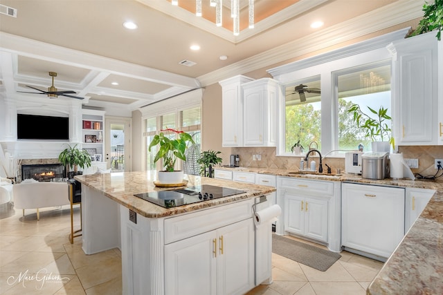 kitchen featuring black electric stovetop, a kitchen island, white cabinetry, sink, and a healthy amount of sunlight