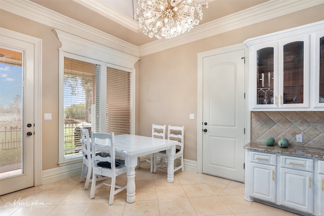 dining space with light tile patterned flooring, crown molding, and a notable chandelier