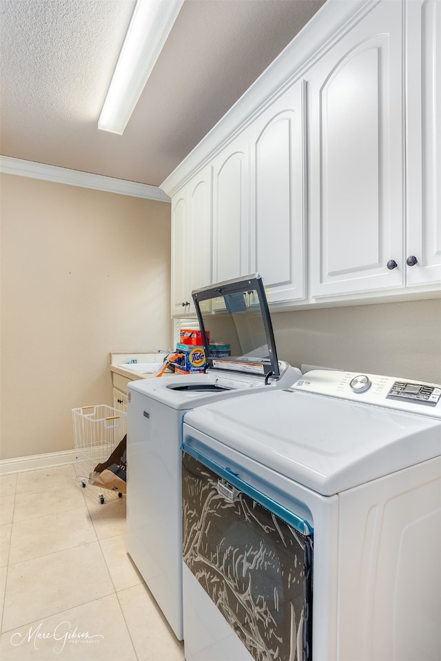 washroom featuring cabinets, washing machine and clothes dryer, ornamental molding, and a textured ceiling