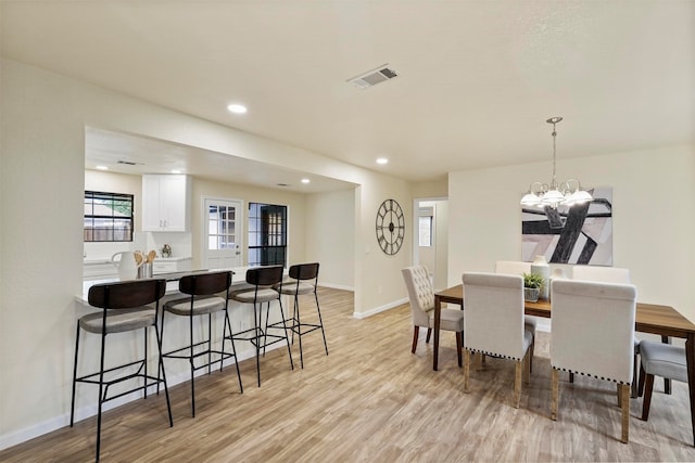 dining area with light wood-type flooring and a chandelier