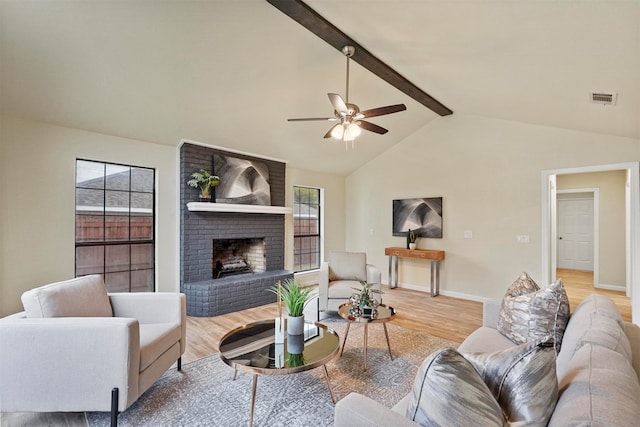 living room with light wood-type flooring, ceiling fan, vaulted ceiling with beams, and a brick fireplace