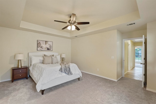 carpeted bedroom featuring ceiling fan and a raised ceiling