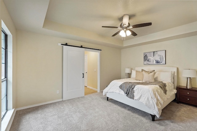 bedroom featuring a barn door, ceiling fan, multiple windows, and light carpet