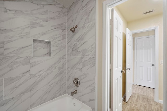 bathroom with wood-type flooring and tiled shower / bath