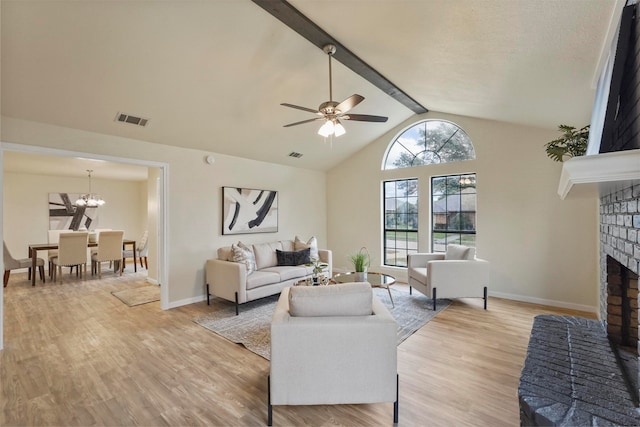 living room with a brick fireplace, light wood-type flooring, ceiling fan with notable chandelier, and vaulted ceiling with beams