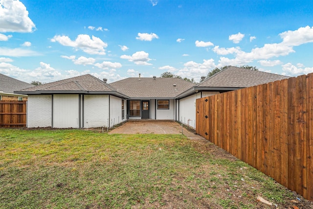 back of house featuring a lawn and a patio