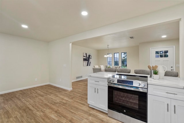 kitchen with light hardwood / wood-style floors, pendant lighting, stainless steel range oven, light stone countertops, and white cabinetry