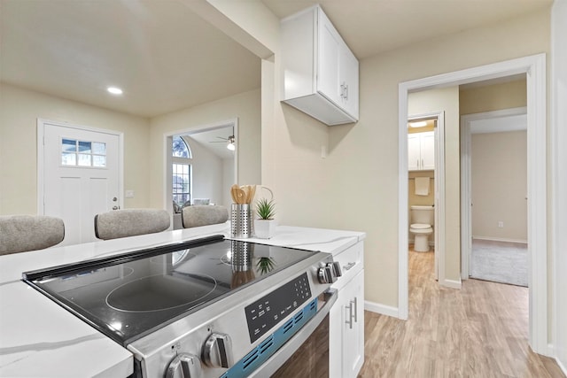 kitchen featuring stainless steel electric range, light hardwood / wood-style floors, light stone counters, white cabinets, and ceiling fan