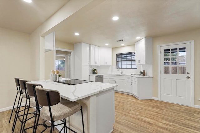 kitchen with white cabinetry, sink, a breakfast bar, and light wood-type flooring