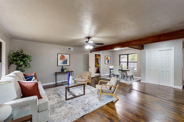 living room featuring dark wood-type flooring, a textured ceiling, ornamental molding, beamed ceiling, and ceiling fan