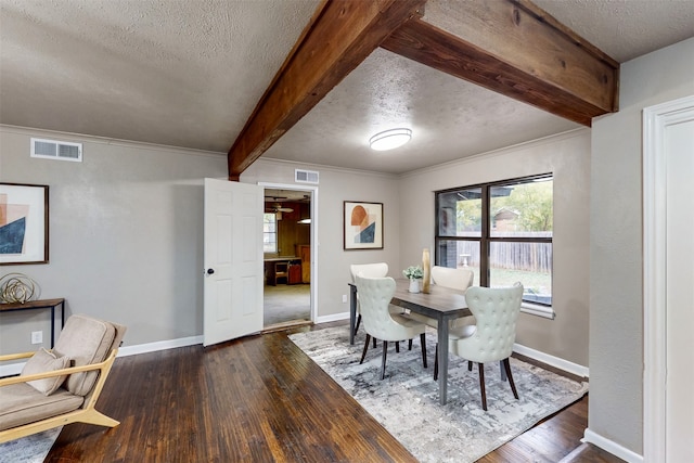 dining space with a textured ceiling, dark hardwood / wood-style flooring, and beamed ceiling