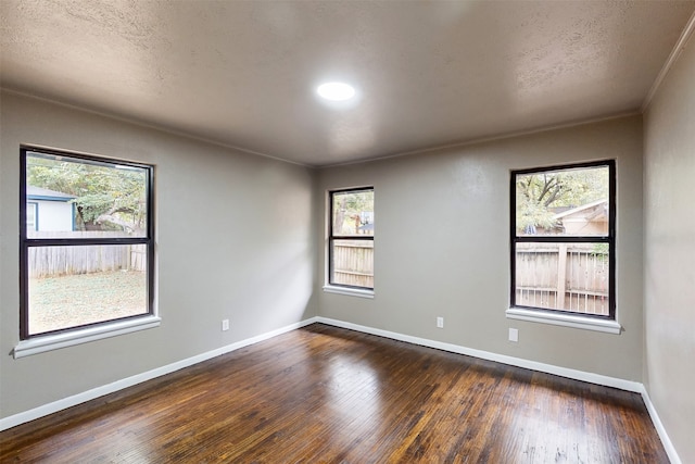 empty room featuring ornamental molding, a textured ceiling, and dark hardwood / wood-style floors