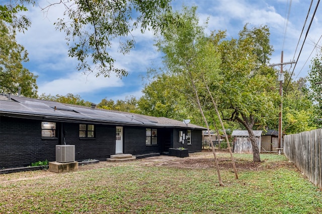 rear view of property with a lawn and cooling unit