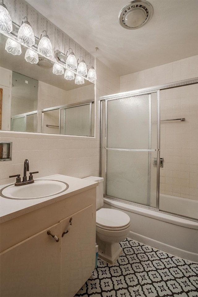 full bathroom with tasteful backsplash, shower / bath combination with glass door, vanity, toilet, and tile walls