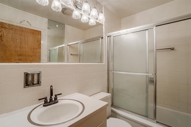 full bathroom featuring decorative backsplash, shower / bath combination with glass door, vanity, toilet, and tile walls