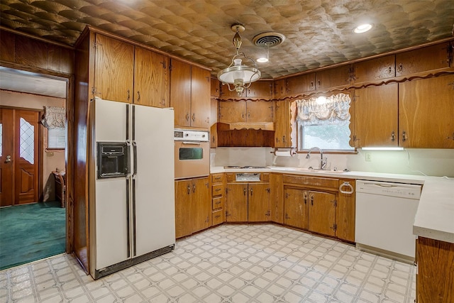 kitchen with decorative light fixtures, sink, and white appliances