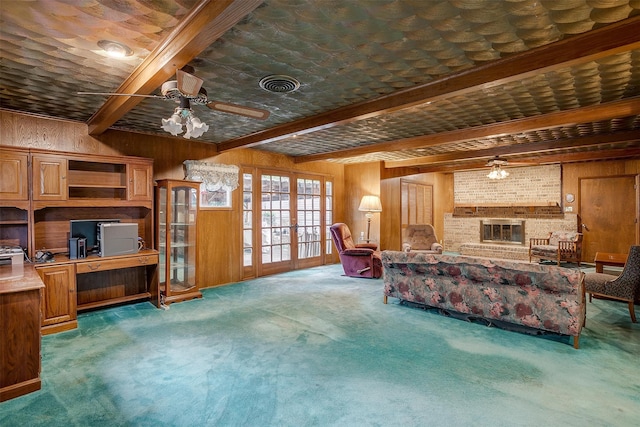 living room featuring a fireplace, beamed ceiling, wooden walls, and french doors