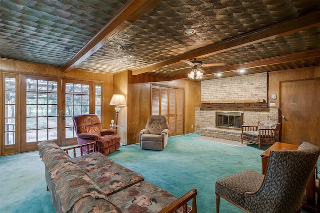 carpeted living room with wood walls, beamed ceiling, french doors, and a fireplace