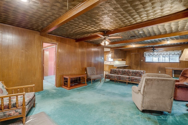 living room with wood walls, ceiling fan, beam ceiling, and carpet