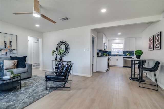 living room with ceiling fan, light hardwood / wood-style floors, and sink