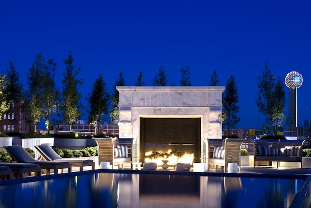 pool at twilight featuring an outdoor fireplace