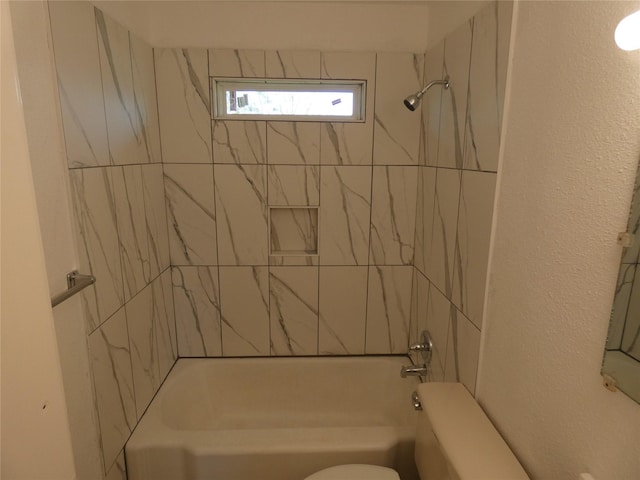 bathroom with toilet and tiled shower / bath