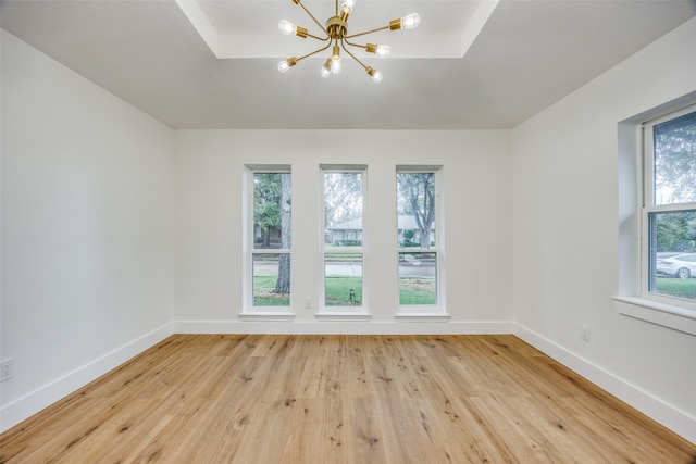 unfurnished room featuring light wood-type flooring and an inviting chandelier