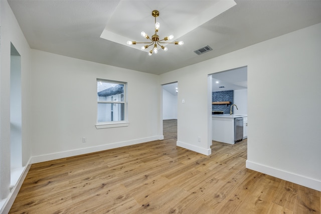 unfurnished room with light hardwood / wood-style flooring, a notable chandelier, and sink