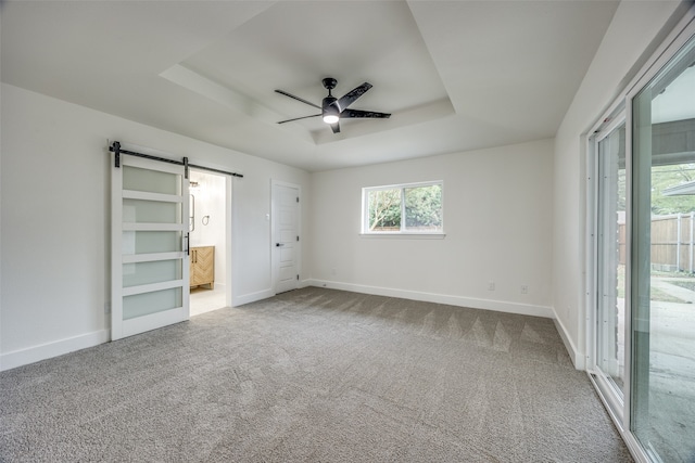 unfurnished bedroom featuring connected bathroom, ceiling fan, carpet floors, and a barn door